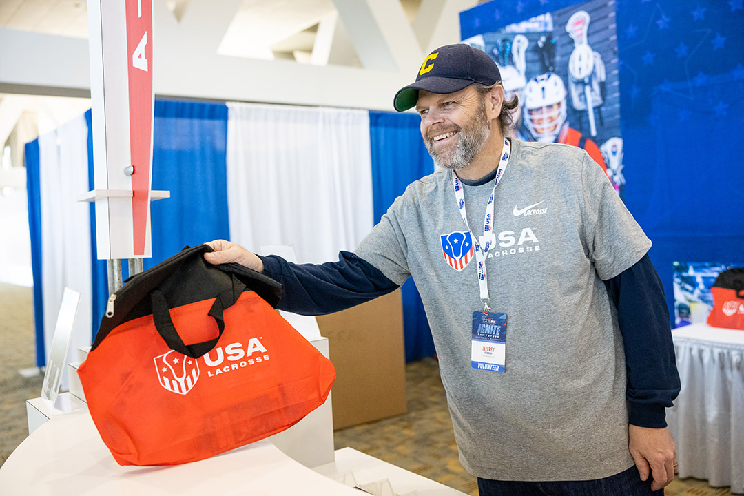Volunteer handing a bag at a USA Lacrosse event